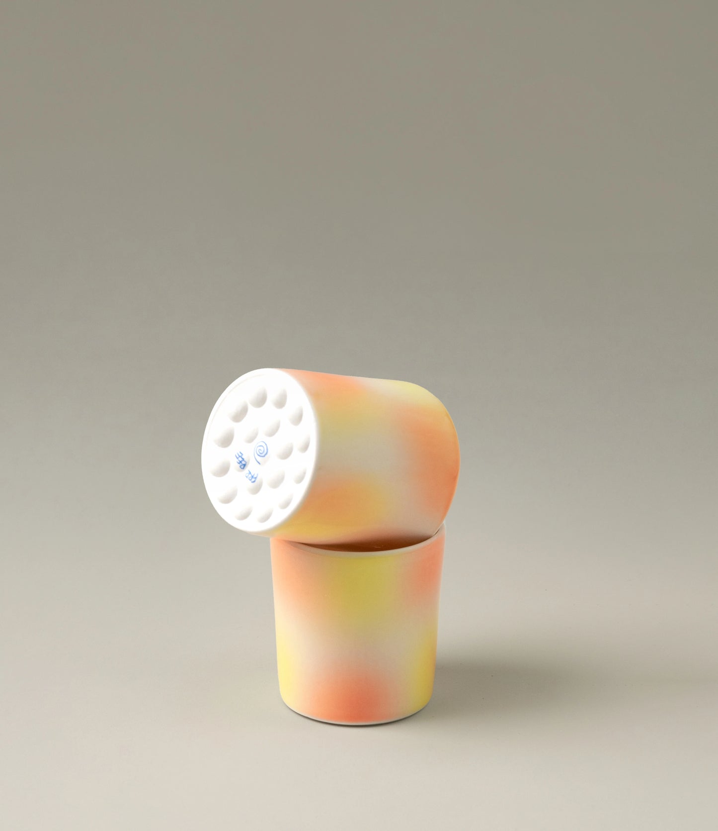 Bulle Cup from Frizbee Ceramics has a unique gradient painted pattern. The cup comes in a set of two and has warm colors like orange, peach and yellow. The bottom of the cup looks like it's made of small bubbles.