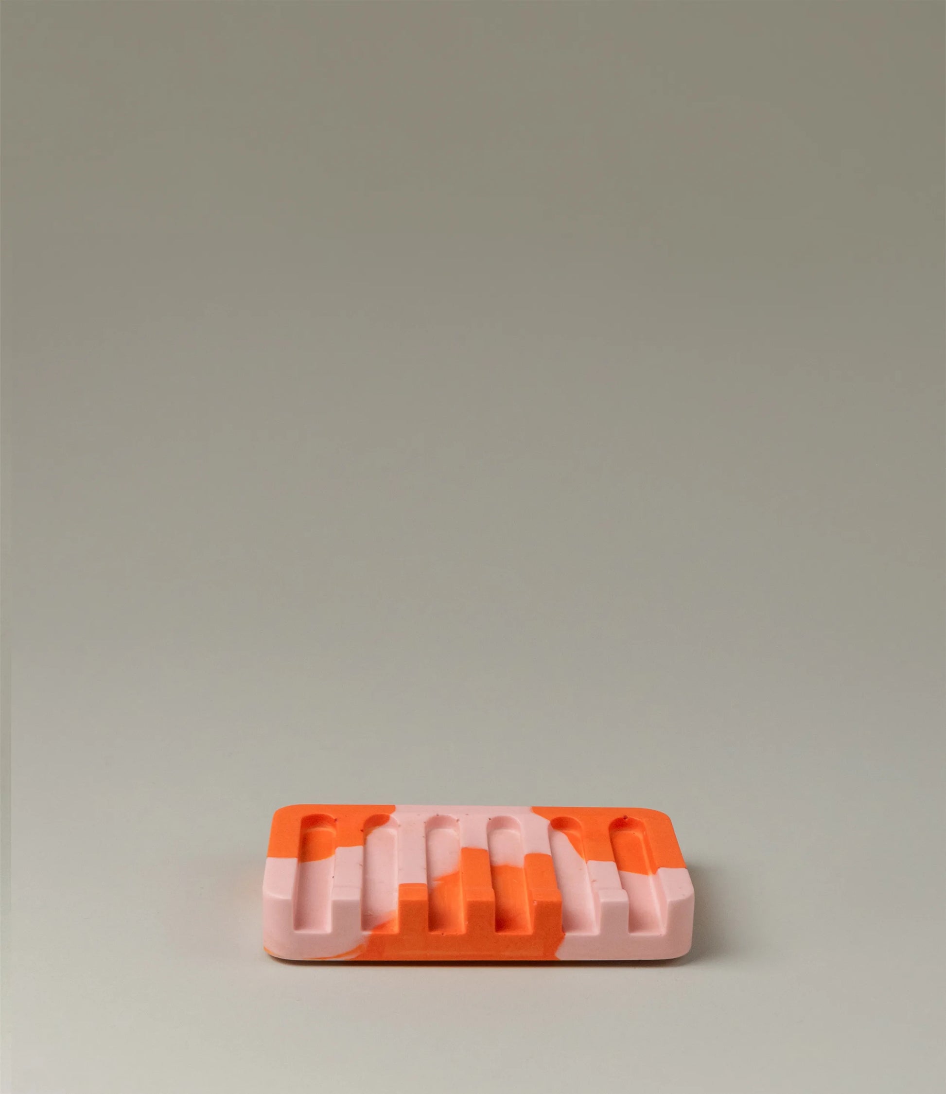 Soap Holder from Gritful Homeware in the maximalist color pairing of light rose and orange. The soap dish has a rectengular shape which contrasts the pattern of the item, which is more organic.