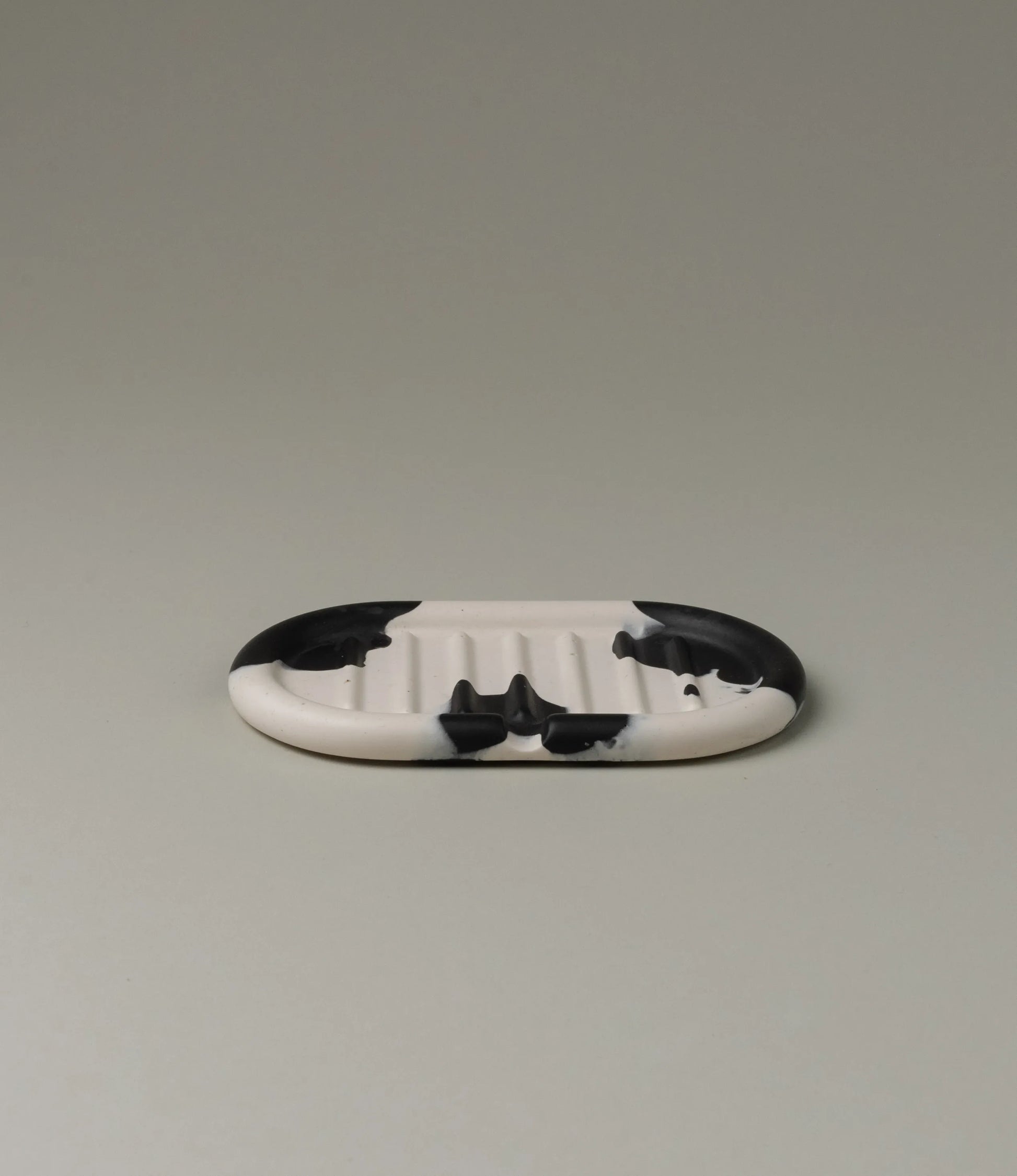 Soap Holder from Gritful Homeware in the minimalist color pairing of black and white. The soap dish has a rectengular shape which contrasts the pattern of the item, which is more organic and resembles paint splashes.