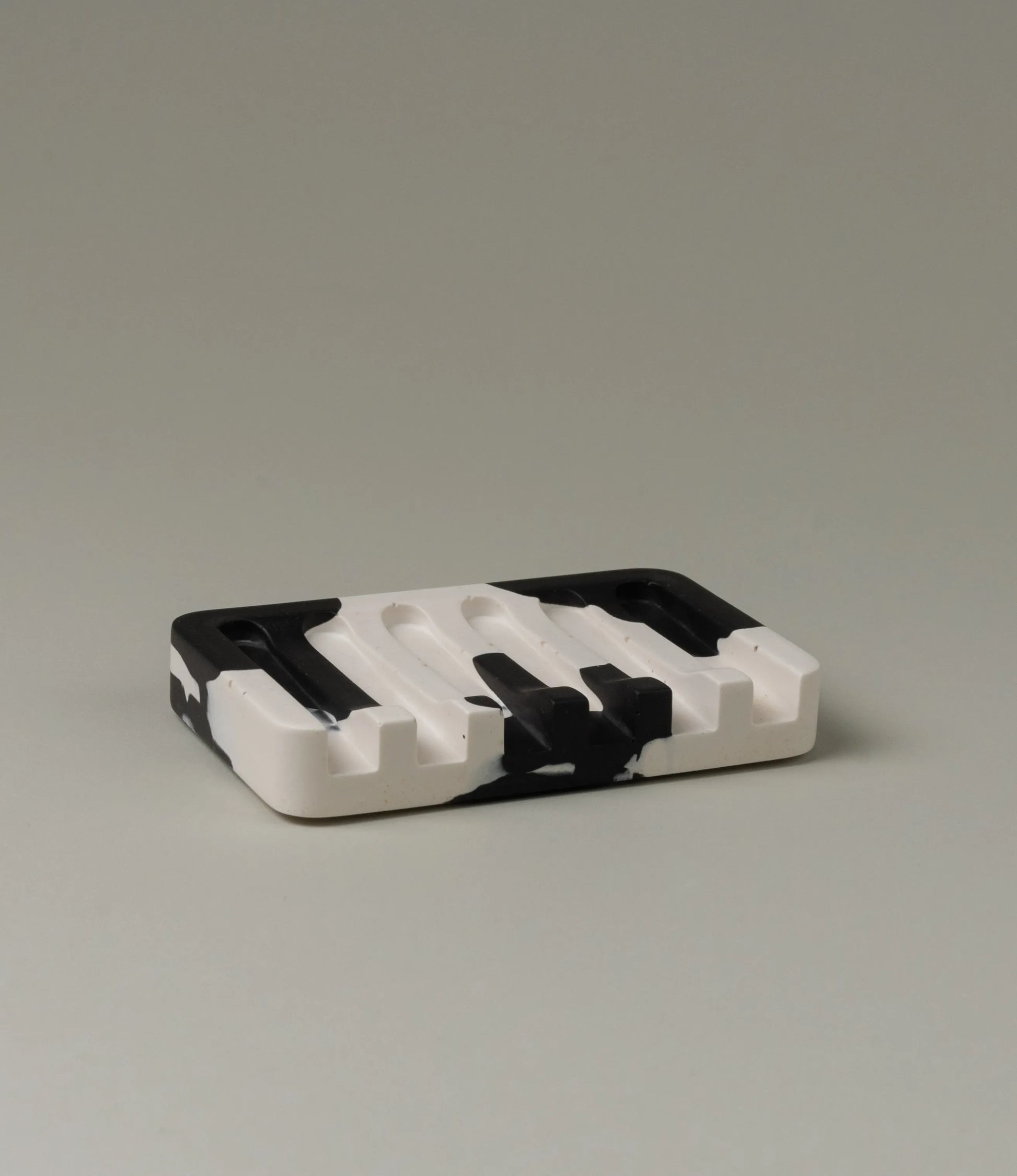 Soap Holder from Gritful Homeware in the minimalist color pairing of black and white. The soap dish has a rectengular shape which contrasts the pattern of the item, which is more organic and resembles paint splashes.