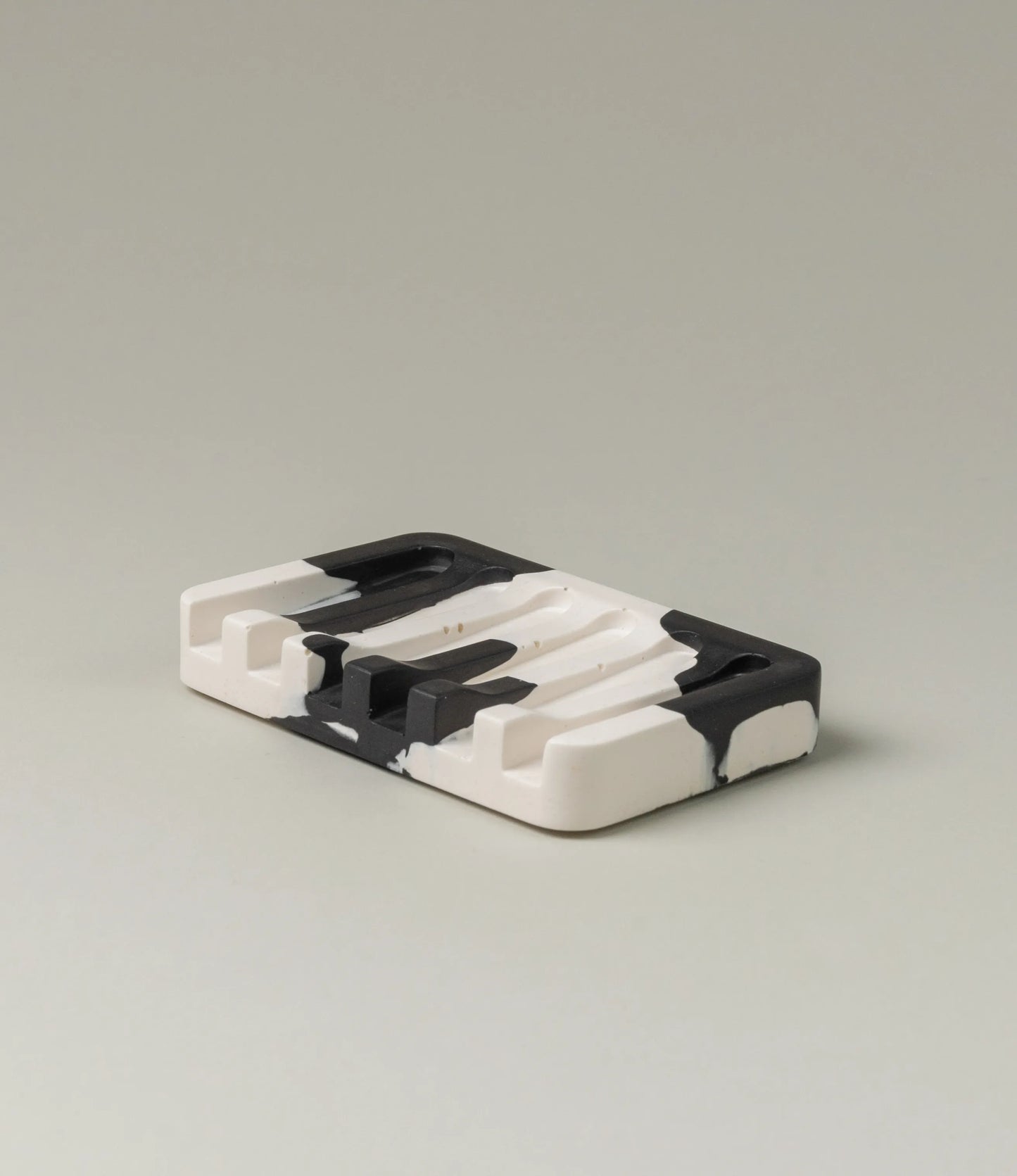 Soap Holder from Gritful Homeware in the minimalist color pairing of black and white. The soap dish has a rectengular shape which contrasts the pattern of the item, which is more organic and resembles paint splashes.