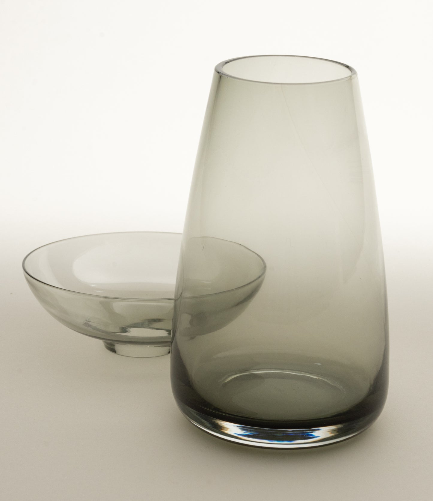 Aqua Culture Vase from Kinto is a vase to grow new plants. The vase consists of two pieces, a base and a dish for the top, which holds the bulbs, seeds or leaves. This variant has a dark, smokey gray color.