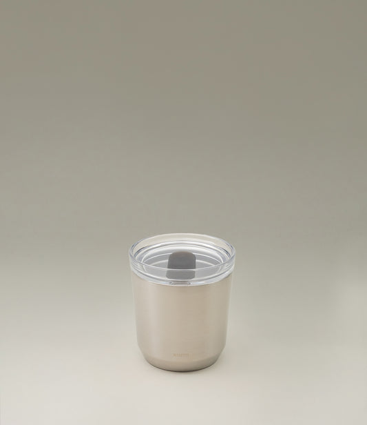 A takeaway cup from the japanese brand 'Kinto'. The To Go Tumbler is a matte stainless steel item, leak proof with a clear top part. The item retains the temperature and taste of your drink.